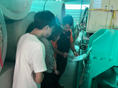 Scene of teacher leading students to conduct on-site inventory at a factory