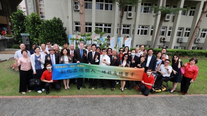 Group photo of guests and teachers in front of the Buddhist pine plant