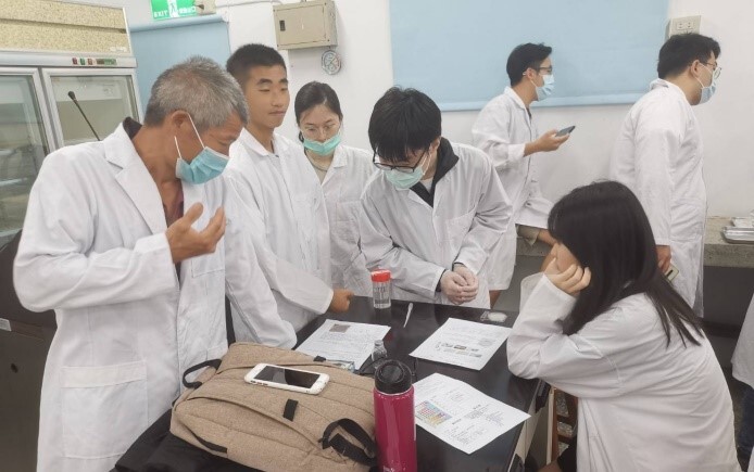 Students discuss experimental data in the lab with Mr Chen, a national model fisherman